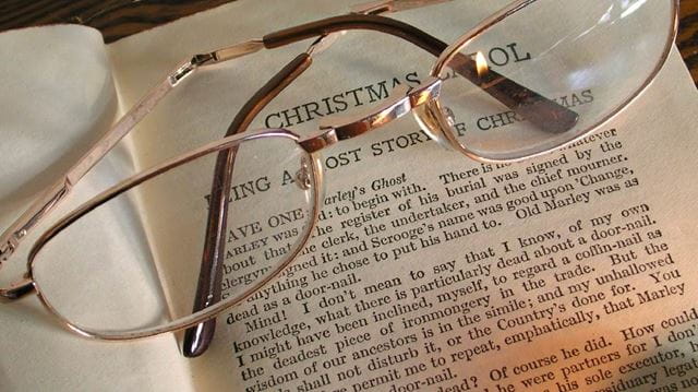 reading glasses on top of a Christmas Carol book